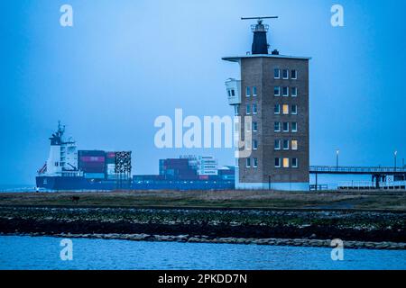 Dichter Nebel im Winter, über der Mündung der Elbe in die Nordsee, Containerschiff fließt in den Elbradarturm der Wasser- und Schifffahrt Stockfoto