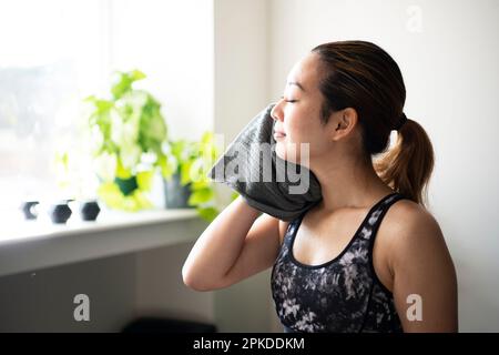 Eine Frau, die eine Pause macht, während sie im Fitnessstudio den Schweiß abwischte Stockfoto