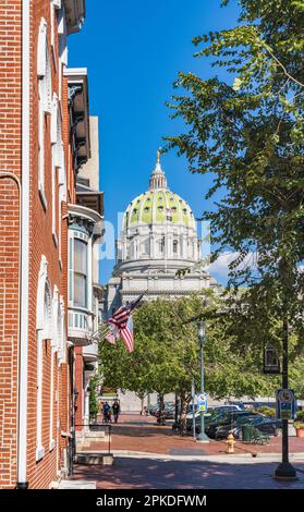 Eine von Bäumen gesäumte Straße mit bezaubernden Backsteingebäuden, die auf das Pennsylvania State Capitol Building in Harrisburg, Pennsylvania, USA, gerichtet ist Stockfoto