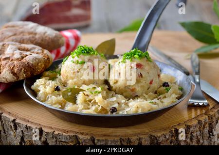 Köstliche südtiroler Speckklöße, serviert auf Sauerkraut in einer eisernen Bratpfanne Stockfoto