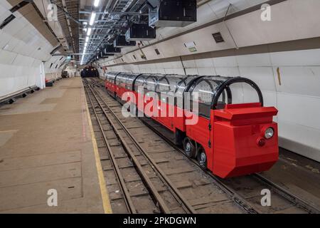 Einer der angepassten Touristenzüge von Mail Rail, dem ehemaligen Postamt-Eisenbahnsystem unter den Straßen von Central London, Vereinigtes Königreich. Stockfoto