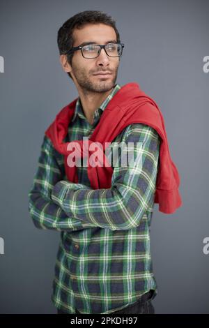 Porträt von Herren, männlich, ruhig, intelligenter Mann mit ernstem Gesichtsausdruck, der auf grauen Hintergrund in die Kamera schaut Stockfoto