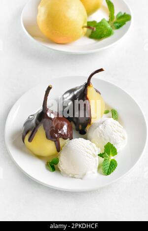 Pochierte Birnen mit Schokoladensoße und Eis auf weißem Hintergrund. Nahaufnahme Stockfoto