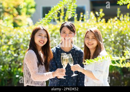 Drei lächelnde Frauen, die auf eine Gartenparty anstoßen Stockfoto