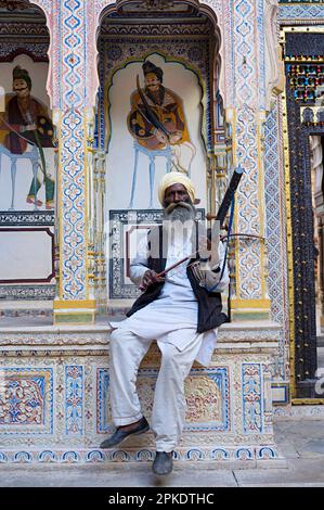 Der alte Shekhavati-Mann spielt ein altes Instrument im Dr. Ramnath Podar Haveli Museum, einem Kulturerbe-Museum, das Rajasthani-Lebensstil beherbergt Stockfoto