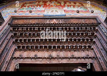 Farbenfrohe Gemälde und geschnitzte Holztür des Kamal Morarka Haveli Museums in Shekhawati. Marwari-Händler bauten große Havelis in den Shekhawati Stockfoto