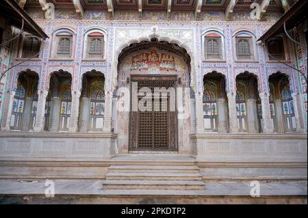 Farbenfrohe Gemälde und geschnitzte Holztür des Kamal Morarka Haveli Museums in Shekhawati. Marwari-Händler bauten große Havelis in den Shekhawati Stockfoto