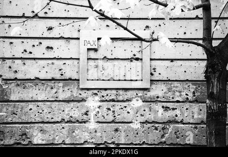 Ostdeutschland, ehemalige DDR, Ostberlin, Kunstwerke, Hausmauer mit Löchern aus dem letzten Kampf zwischen der roten sowjetarmee und deutschen Nazisoldaten im Jahr 1945 während des Zweiten Weltkriegs, Rahmen mit Wort PAX Peace, historisches Schwarz-Weiß-Bild, aufgenommen auf 35-mm-Film Stockfoto