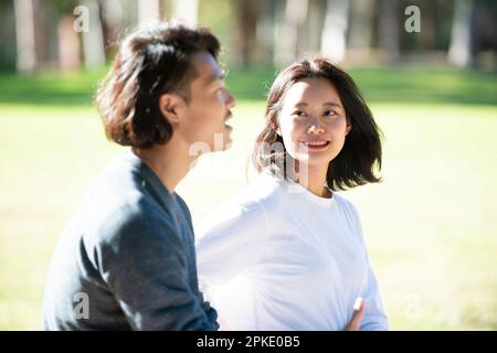 Zwei Männer und eine Frau, die auf dem Rasen sitzen und reden Stockfoto