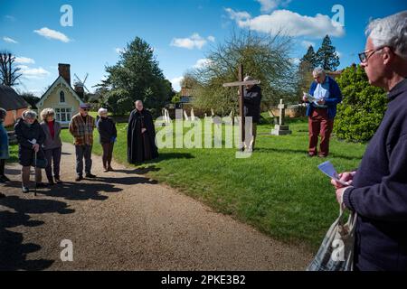 Thaxted, England, Gb 07. April 2023. Thaxted Essex UK Zeugenprozession am Karfreitag 7. April 2023 Daniel Fox trägt das christliche Kreuz der Opfer, während er die Prozession am Osterfreitagmorgen durch die wunderschöne Stadt Thaxted im Nordwesten von Essex führt. Hier mit Thaxted Alms House und Chantry und Hohn Webbs Windmill im Hintergrund. Kredit: BRIAN HARRIS/Alamy Live News Stockfoto