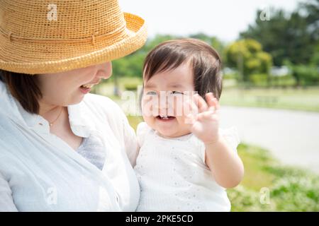 Lachendes Baby, das von der Mutter getragen wird Stockfoto