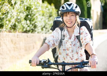 Weiblicher Liefermann auf einem Fahrrad Stockfoto