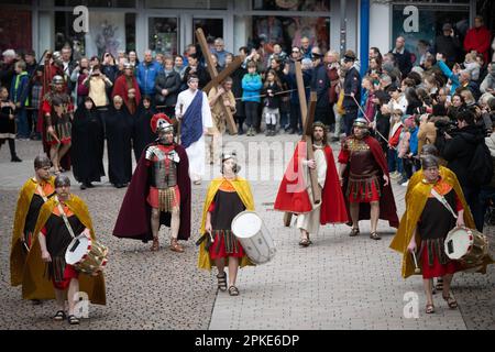 Bensheim, Deutschland. 07. April 2023. Jesus (Julian Lux) trägt das Kreuz während der Karfreitagsprozession durch das Stadtzentrum. Rund 90 Amateurschauspieler und Schauspielerinnen in historischen Kostümen führen durch die Innenstadt von Bensheim und stellen die Stationen des Kreuzes nach. Die Prozession wird von der Vereinigung „Bensheim Italian Families and German Friends“ organisiert. Das Ereignis findet zum ersten Mal seit der Corona-Pandemie statt. Kredit: Sebastian Christoph Gollnow/dpa/Alamy Live News Stockfoto