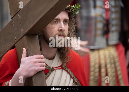 Bensheim, Deutschland. 07. April 2023. Jesus (Julian Lux) trägt das Kreuz während der Karfreitagsprozession durch das Stadtzentrum. Rund 90 Amateurschauspieler und Schauspielerinnen in historischen Kostümen führen durch die Innenstadt von Bensheim und stellen die Stationen des Kreuzes nach. Die Prozession wird von der Vereinigung „Bensheim Italian Families and German Friends“ organisiert. Das Ereignis findet zum ersten Mal seit der Corona-Pandemie statt. Kredit: Sebastian Christoph Gollnow/dpa/Alamy Live News Stockfoto