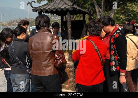 Gläubige sammeln sich um eine Sandschale oder durch den Boden des A-Ma Tempels in Macau, China, zu leichten Handvoll Joss-Sticks. Der Tempel, gewidmet der taoistischen Muttergöttin A-Ma oder Tin Hau, Beschützerin der Seeleute, stammt aus dem Jahr 1488 n. Chr. und wurde an der Stelle erbaut, an der sie angeblich nach einem Schiffswrack gelandet ist. Stockfoto