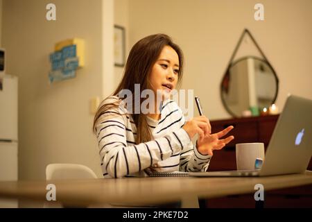 Frau, die an einem Ferngespräch von zu Hause aus teilnimmt Stockfoto