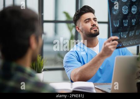 Der Arzt und der Patient an der Rezeption sprechen über das Röntgenbild der Nebenhöhlen. Stockfoto