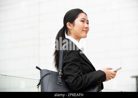 Frau im Anzug, die ein Handy hält Stockfoto