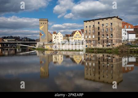 Neisse Shore in Zgorzelec. Uferwand mit Graffiti bemalt. Gebäude werden auf dem Wasser reflektiert. Fußgängerbrücke nach görlitz. Stockfoto