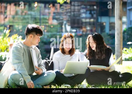 3 Schüler, die draußen an einem Computer studieren Stockfoto