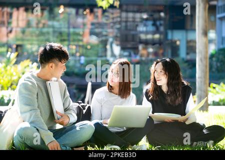 3 Schüler, die draußen an einem Computer studieren Stockfoto