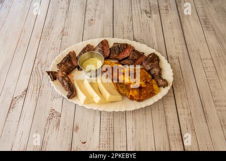 Tablett mit Barbecue im lateinamerikanischen Stil mit frischem Käse und gebratenen Kochbananen Stockfoto