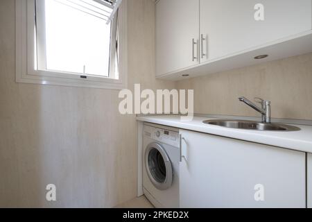 Kleine Küche mit integrierten Geräten und Edelstahl-Wasserhahn und einem Fenster mit Kipp-and-Turn-Funktion Stockfoto