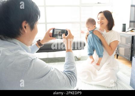 Vater filmt Baby und Mutter, die zu Hause spielen Stockfoto