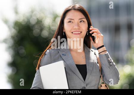 Eine Frau im Anzug, die ein Telefon in der Hand hält und einen Anruf tätigt Stockfoto