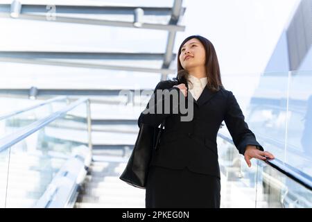 Eine Frau im Anzug, die Rolltreppe fährt Stockfoto