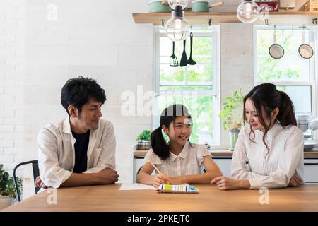 Eltern beobachten ein Mädchen der Grundschule, das studiert Stockfoto