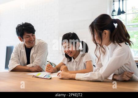 Eltern beobachten ein Mädchen der Grundschule, das studiert Stockfoto