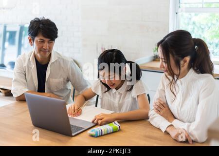 Eltern beobachten ein Mädchen der Grundschule, das studiert Stockfoto