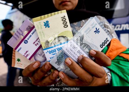 Medan, Indonesien. 07. April 2023. Eine Frau zeigt am 7. April 2023 kleine Rupiah-Stückelungen aus dem Drive-Thru-System bei einem mobilen Bargeldservice in Medan, Provinz Nordsumatra, Indonesien. Der Umtausch von Rupiah-Stückelungen ist als Geschenkgeld für Familienmitglieder bei Feiern des Eid Al-Fitr gedacht. (Foto: Hendro Budiman/INA Photo Agency/Sipa USA) Guthaben: SIPA USA/Alamy Live News Stockfoto