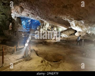 28. Februar 2023, Vietnam, Halong-Bucht: Besucher spazieren durch die Überraschungshöhle (Hang Sung Sot). Die Höhle Sung Sot befindet sich auf der Insel Bo Hòn und wurde erstmals 1901 von französischen Entdeckern entdeckt. Die riesige Höhle erstreckt sich über eine Fläche von mehr als 12.200 Quadratmetern und besteht aus drei kleineren Abteilungen oder „Räumen“, die jeweils mit beeindruckenden Stalaktiten gefüllt sind. Die Halong-Bucht (vietnamesisch: Vinh Ha Long) ist eine Fläche von etwa 1.500 Quadratkilometern im Golf von Tonkin in der Provinz Quang Ninh im Norden Vietnams. 1994 wurde die Bucht von der UNESCO zum Weltkulturerbe erklärt. Foto: Alexandra Schuler/dpa Stockfoto