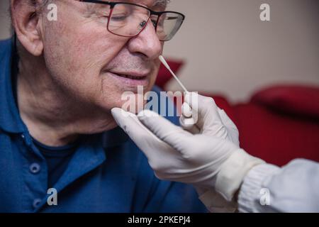 Nahaufnahme eines älteren Patienten, der mit einem molekularen Abstrich auf der Nase auf COvid-19 getestet wurde. Stockfoto