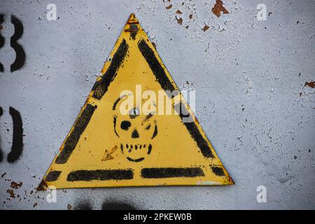 Gelbes Warnschild mit Schädel an der Transformatorkabine Stockfoto