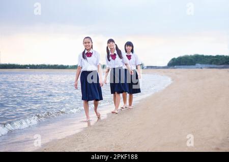 Schüler der Mittelstufe, die am Strand spazieren gehen Stockfoto