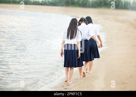 Schüler der Mittelstufe, die am Strand spazieren gehen Stockfoto