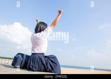 Schüler der Junior High School dehnen sich, während sie am Ufer sitzen Stockfoto