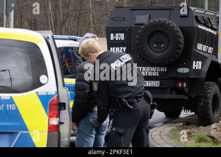 07. April 2023, Hessen, Weiterstadt: Ein gepanzertes Auto des Sicherheitsdienstes steht nach einer Polizeioperation im Servicegebiet Gräfenhausen. Im Vordergrund kontrolliert ein Polizist einen Wachmann. LKW-Fahrer streiken an der Raststätte – nun wollte der Besitzer der Fahrzeuge Zugang zu den LKWs mit einer Gruppe von bezahlten Sicherheitsdiensten erhalten. Die Polizei musste die privaten Sicherheitsleute zurückdrängen. 16 Personen wurden vorübergehend inhaftiert. Die rund 50 Fernfahrer des polnischen Unternehmens streiken seit mehreren Tagen im Servicebereich. Foto: Sebastian Gollnow/d Stockfoto