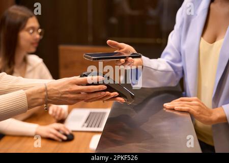 Stilvoller Besucher, der kontaktlose Transaktionen an der Rezeption in der Lobby tätigt Stockfoto