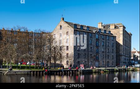 Leith, Edinburgh, Schottland, Großbritannien, 7. April 2023. Wetter in Großbritannien: Sonnenschein auf Leith. Das herrliche sonnige Wetter am Karfreitag bringt die Menschen dazu, am Ufer des Wassers von Leith in der Sonne zu sitzen. Kredit: Sally Anderson/Alamy Live News Stockfoto