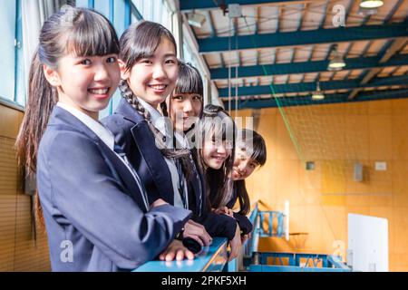 Das Mädchen der Junior High School lehnt sich gegen den Handlauf im zweiten Stock des Gymnasiums Stockfoto