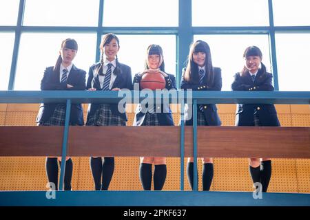Die Mädchen der Junior High School lehnen sich gegen den Handlauf im zweiten Stock des Gymnasiums Stockfoto