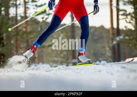 Beine Skifahrer auf der Skipiste, Schneespritzer unter Skiern und Stöcken, Wintersportwettbewerb Stockfoto