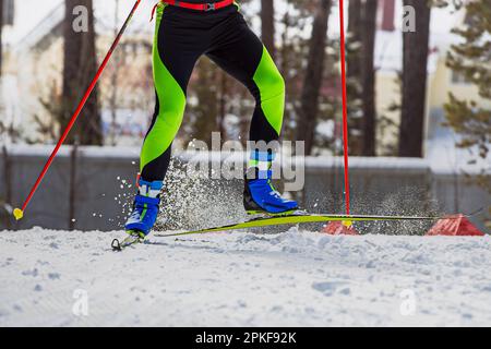 Nahaufnahmen der Beine Skifahrer laufen auf der Skipiste, Schnee spritzt unter Skiern und Stöcken, Wintersportwettbewerb Stockfoto