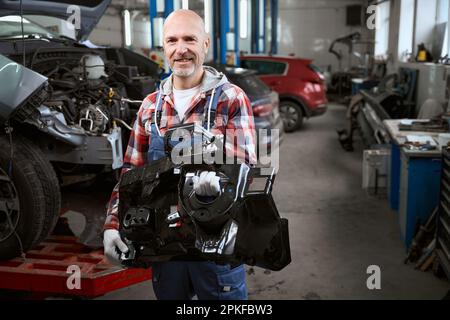 Ein Mann in einem karierten Hemd mit einem Ersatzteil in der Hand Stockfoto