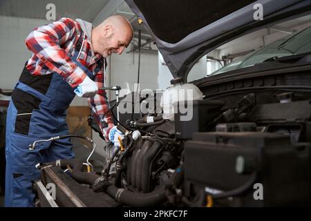 Ein Arbeiter in einer Autoreparaturwerkstatt repariert ein Auto Stockfoto