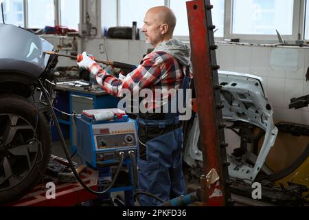 Der Automechaniker arbeitet als Spotter für die Fahrzeugreparatur Stockfoto